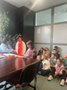Dziecko stoi przed kołem fortuny, reszta grupy siedzi na podłodze.