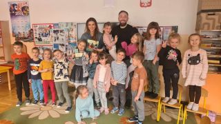 dzieci z gośćmi pozują do zdjęcia na dywanie