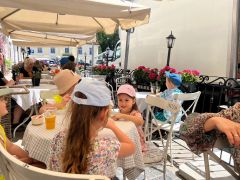 dzieci siedzą pod parasolami w ogródku restauracji