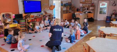 dzieci siedzą na dywanie z panią Policjantką