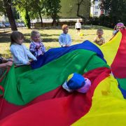 dzieci z paniami bawią się chustą na placu przedszkolnym