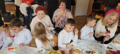 Zaproszeni goście stoją i siedzą na krzesłach