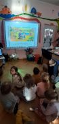 Dzieci siedzą przy tablicy multimedialnej.