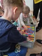 Dzieci siedzą na dywanie, oglądają książki.