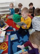 Dzieci siedzą na dywanie czytają książki