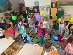 Dzieci w sali bawią się z balonami