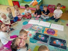 Dzieci wykonują zadania z pajęczyną relacji na dywanie.