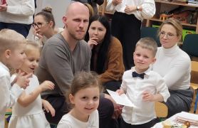 Dzieci przy stolikach konsumują smakołyki wigilijne.