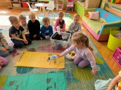 Dzieci podczas zajęć edukacyjnych w sali segregują  śmieci.