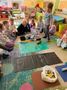 Zajęcia edukacyjne dzieci segregują śmieci na dywanie.