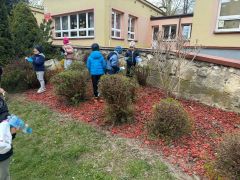 Dzieci sprzątają okolice przedszkola segregują śmieci.