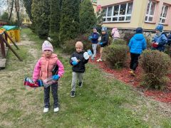 Dzieci sprzątają okolice przedszkola segregują śmieci.